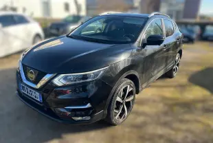 Nissan Qashqai noir vu en 3/4 avant droit, avec jantes alliage et barres de toit visibles.
