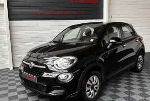 Vue 3/4 avant droit d'une Fiat 500X noire 2018 dans un garage avec sol carrelé gris et blanc.