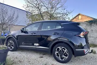 KIA SPORTAGE noir vu de profil côté gauche, avec jantes alliage et attelage de remorque visible à l'arrière.