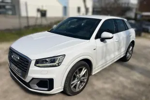 Audi Q2 blanc vue 3/4 avant droit, avec jantes alliage et calandre noire distinctive S-Line.