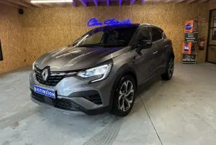 Renault Captur gris 3/4 avant droit en intérieur, avec phares allumés et jantes distinctives RS Line.
