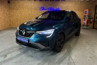 Renault Arkana bleu 3/4 avant droit en intérieur, avec calandre noire et phares LED allumés.