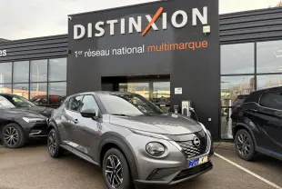 Nissan Juke II 1.6 Hybrid noir métal en 3/4 avant droit, avec jantes alliage et calandre distinctive, devant un showroom.