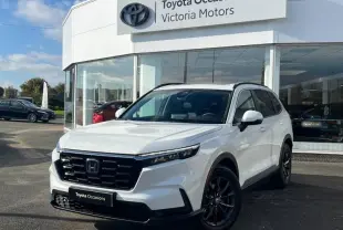 Honda CR-V 2024 blanc diamant métallisé en 3/4 avant droit avec calandre noire et jantes foncées, devant concession Toyota.