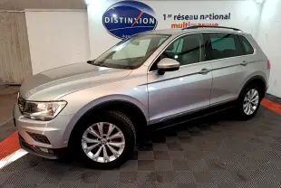 Volkswagen Tiguan gris clair vu de profil côté gauche dans un showroom avec logo Distinxion en arrière-plan