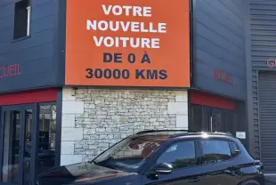 Citroën C3 noire vue en 3/4 avant droit, avec jantes 16 pouces et toit avec rails noirs devant un bâtiment commercial.