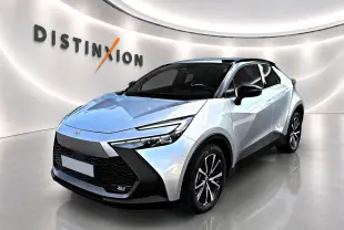 Toyota C-HR gris 3/4 avant droit avec toit noir et jantes alliage dans un showroom lumineux.