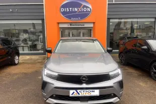 Vue avant d'un Opel Grandland gris Kontrast métallisé garé devant une concession avec calandre noire brillante et phares LED.