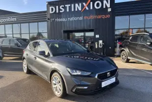 SEAT Leon IV gris magnetic vue 3/4 avant droit, jantes alliage 16 pouces, stationnée devant un showroom Distinxion.
