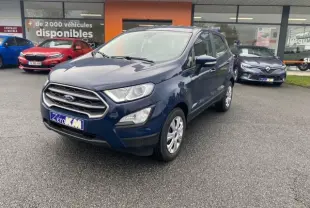 Ford EcoSport bleu abysse en 3/4 avant droit, avec calandre chromée et feux de jour LED visibles sur parking.