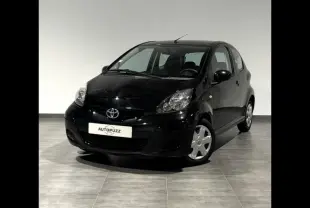 Vue 3/4 avant d'une Toyota Aygo noire de 2009 avec trois portes, sur sol carrelé en intérieur.