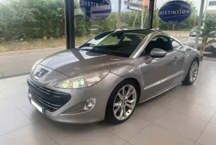 Peugeot RCZ gris en 3/4 avant droit, avec jantes alliage et toit panoramique visible en showroom.