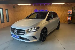Vue 3/4 avant droite d'une Mercedes Classe B 200D Progressive Line gris métallisé avec jantes noires en intérieur showroom.