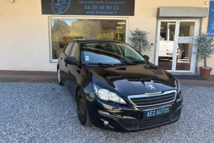 Peugeot 308 Active noire vue en 3/4 avant droit, stationnée devant un garage AE2 Autos sur gravier.