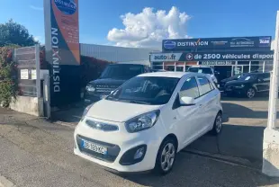Vue 3/4 avant d'une KIA Picanto 1.0 Active 2013 blanche, stationnée devant un concessionnaire Distinxion.