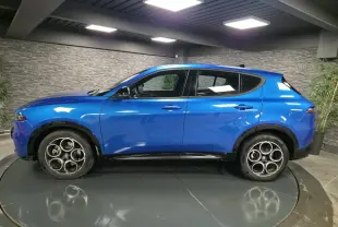 Vue de profil côté gauche d'un Alfa Romeo Tonale bleu métallisé avec jantes alliage 18 pouces dans un showroom.