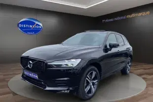 Volvo XC60 noir en 3/4 avant droit, avec toit panoramique et jantes alliage visibles dans un showroom.