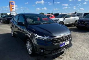 Dacia Logan gris vue 3/4 avant droit sur parking, avec calandre noire et phares LED distinctifs.