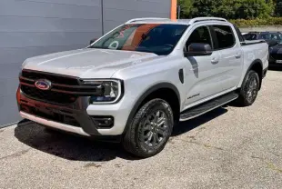 Ford Ranger 2025 gris iconic en 3/4 avant droit, avec calandre noire et jantes alliage foncé Wildtrak Plus.