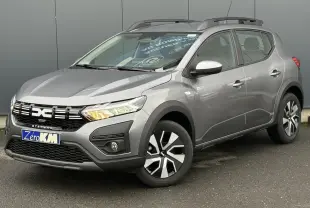 Vue 3/4 avant d'une Dacia Sandero Stepway 2025 gris schiste avec barres de toit et jantes spécifiques Atara Dark.
