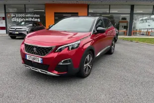 Peugeot 3008 GT Line rouge Ultimate vue 3/4 avant droit avec toit noir et jantes alliage bi-ton devant un showroom.