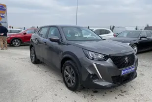 Peugeot 2008 gris foncé vue 3/4 avant droit sur parking avec calandre noire et feux LED griffés.