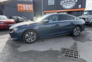 Peugeot 508 bleu métallisé vue de profil côté gauche, avec jantes alliage et vitres surteintées, stationnée devant un garage.