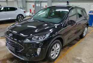 Ford Kuga noir Obsidien vu en 3/4 avant droit dans un garage, mettant en valeur ses phares et sa calandre.
