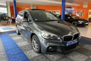 BMW Série 2 Gran Tourer gris en 3/4 avant droit, avec phares LED et calandre caractéristique en intérieur showroom.