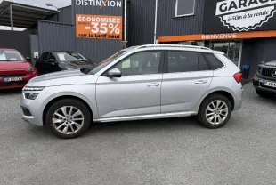 Profil côté gauche d'un Skoda Kamiq gris métallisé 2022 garé devant un garage avec jantes alliage 17 pouces.