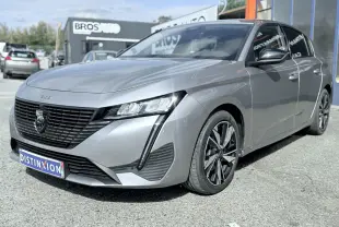 Peugeot 308 gris vue 3/4 avant droit, avec calandre noire et jantes bi-ton distinctives.