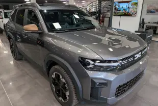 SUV Dacia Bigster Hybrid-G 150 4x4 gris schiste vu en 3/4 avant droit avec rétroviseurs bronze et jantes noires.
