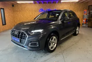 Audi Q5 gris en 3/4 avant droit, avec calandre large et jantes en alliage à 5 branches doubles.