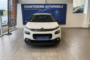Citroën C3 Blanc Banquise vue de face en intérieur, avec calandre noire et feux avant distinctifs.