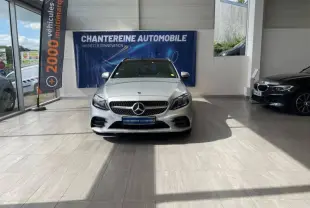 Vue frontale d'une Mercedes Classe C Break 300 d AMG Line argent iridium exposée en showroom avec calandre chromée et logo Mercedes visible.