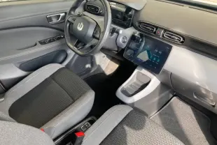 Intérieur du Leapmotor T03 2025 vu côté conducteur, tableau de bord gris clair avec écran tactile et volant multifonction noir.