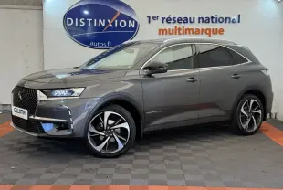 Vue de profil côté gauche d'un DS7 Crossback gris foncé avec jantes alliage et toit chromé dans un showroom.