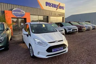 Vue 3/4 avant d'une Ford B-MAX blanche garée devant un concessionnaire Distinxion par temps clair.