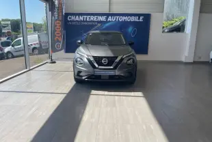 Vue frontale d'un Nissan Juke gris squale métallisé exposé en showroom avec logo Nissan bien visible sur la calandre.