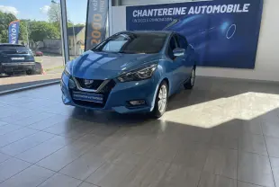 Nissan Micra bleu en 3/4 avant droit dans un showroom avec bannière Chantereine Automobile en arrière-plan.