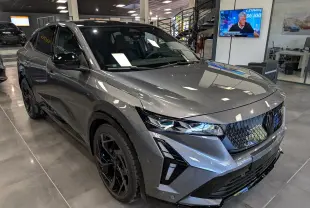 Renault Rafale hyper hybrid gris schiste en 3/4 avant droit, avec calandre noire et jantes noires distinctives.