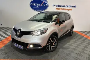 Renault Captur gris en 3/4 avant droit avec jantes alliage et feux allumés dans un showroom.