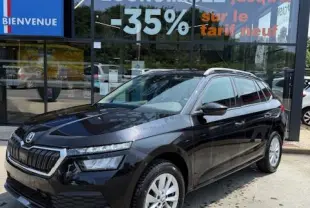 Vue 3/4 avant droite d'un Skoda Kamiq noir 2024 garé devant une vitrine de concession multimarque.