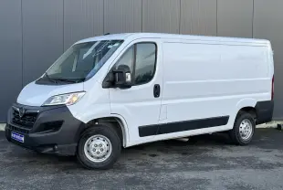 Vue 3/4 avant droit d’un fourgon Opel Movano blanc avec pare-chocs noirs et porte latérale coulissante.