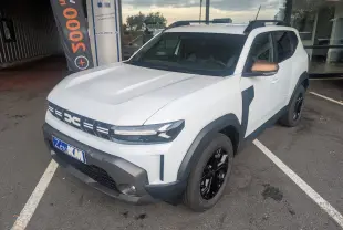 Vue 3/4 avant droite du Dacia Duster Hybrid 155 Extreme blanc glacier avec coques de rétroviseurs brun cuivré et jantes noires 17 pouces.