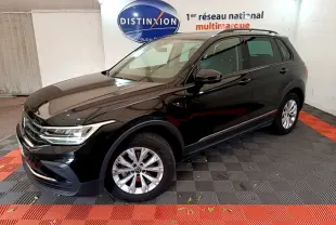 Volkswagen Tiguan noir 2021 vu en 3/4 avant droit dans un showroom avec sol noir et rouge.