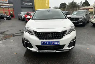 Vue frontale d'un Peugeot 3008 blanc nacré avec calandre noire et plaque Distinxion sur un parking humide.