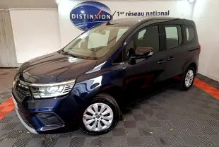 Renault Kangoo Equilibre TCe 100 bleu en 3/4 avant droit, avec phares LED et jantes alliage visibles en intérieur showroom.