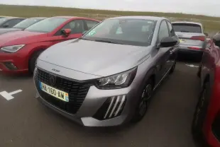 Peugeot 208 gris clair vue 3/4 avant droit avec calandre noire et feux à signature LED 3 griffes.