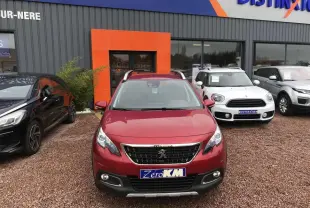 Vue de face d'un Peugeot 2008 rouge Ultimate garé devant un concessionnaire avec toit ouvrant et barres de toit.